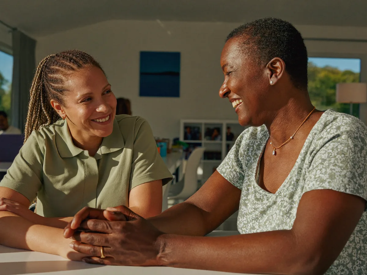 A care professional sharing a warm, unhurried moment with an adult guest during a daytime activity